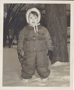 Young girl, about age 2, standing in the snow wearing a snow suit